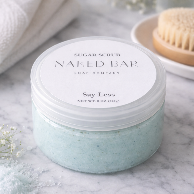 Jar of emulsified sugar scrub with 'Naked Bar Soap Company' label on a marble surface.
